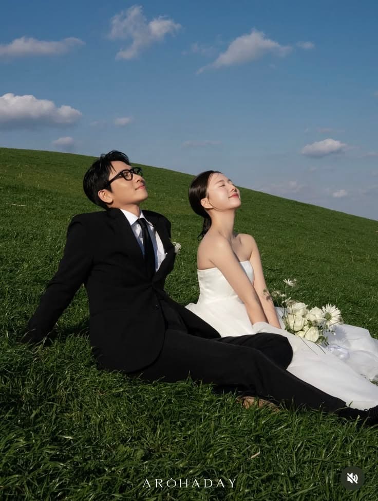 Dion and Ajeng standing hand in hand in a green field