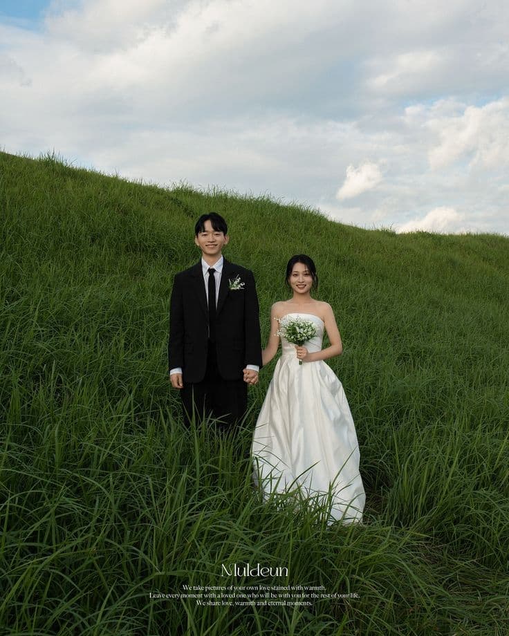 Dion and Ajeng sitting together on a grassy hill